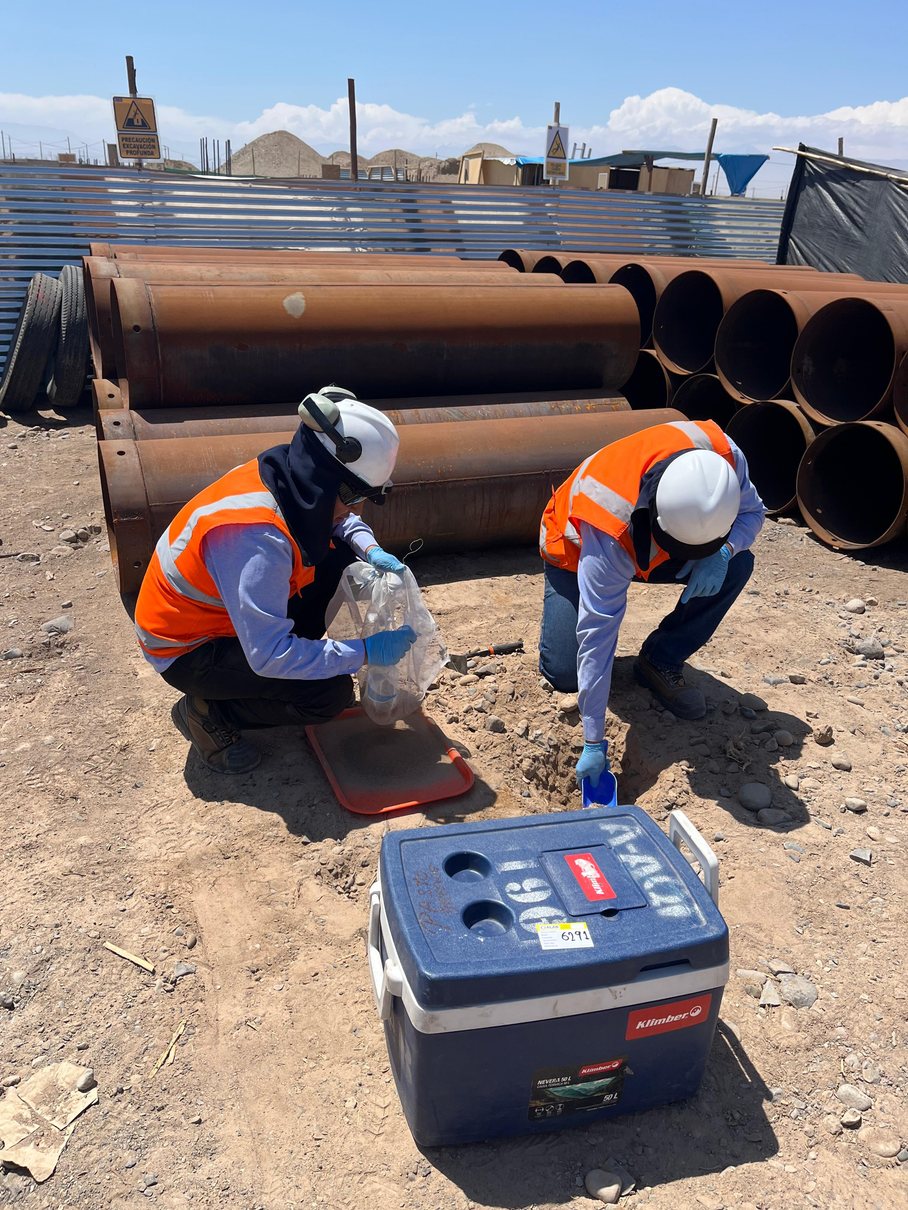 Técnicos de Biomás tomando muestras en campo junto a tubería industrial